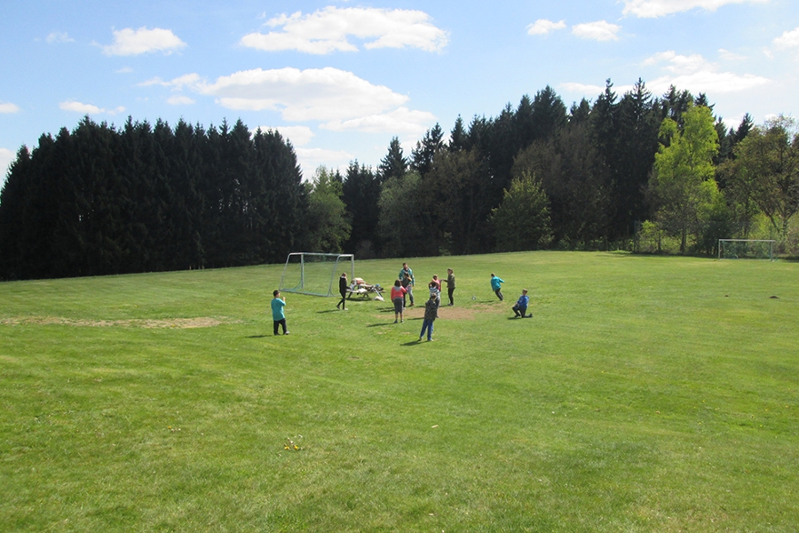 Eine Kindergruppe spielt auf großer Rasenfläche Fußball. Eine Kindergruppe spielt auf großer Rasenfläche Fußball.