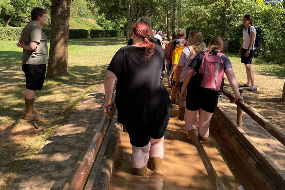 Jugendliche gehen barfuß durch ein Schlammbecken Jugendliche gehen barfuß durch ein Schlammbecken