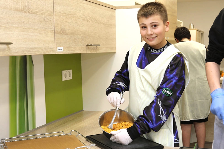 Ein Kind kocht in der Lehrküche eine gesunde Mahlzeit.