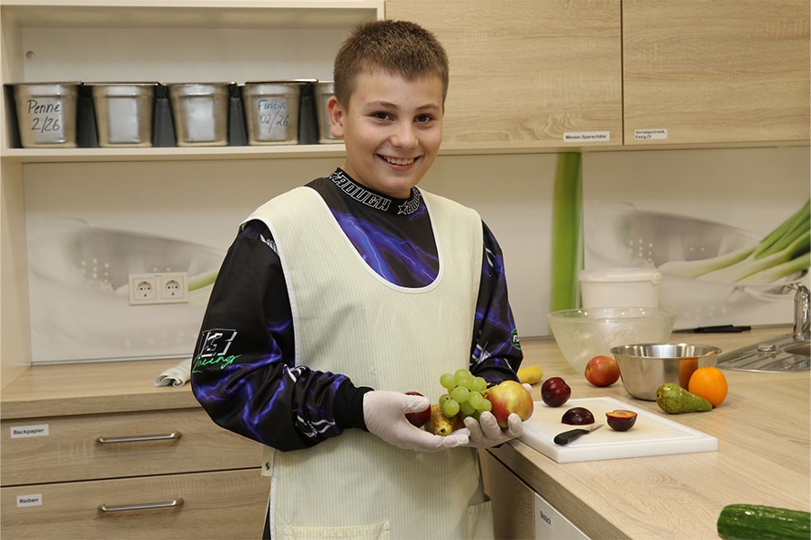 Junge hält frisches Obst in den Händen und lächelt in die Kamera