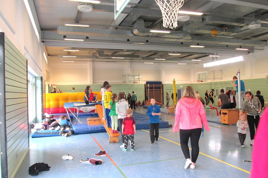 Eltern und ihre Kinder sind in der Sporthalle bei verschiedenen Stationen. Eltern und ihre Kinder sind in der Sporthalle bei verschiedenen Stationen.